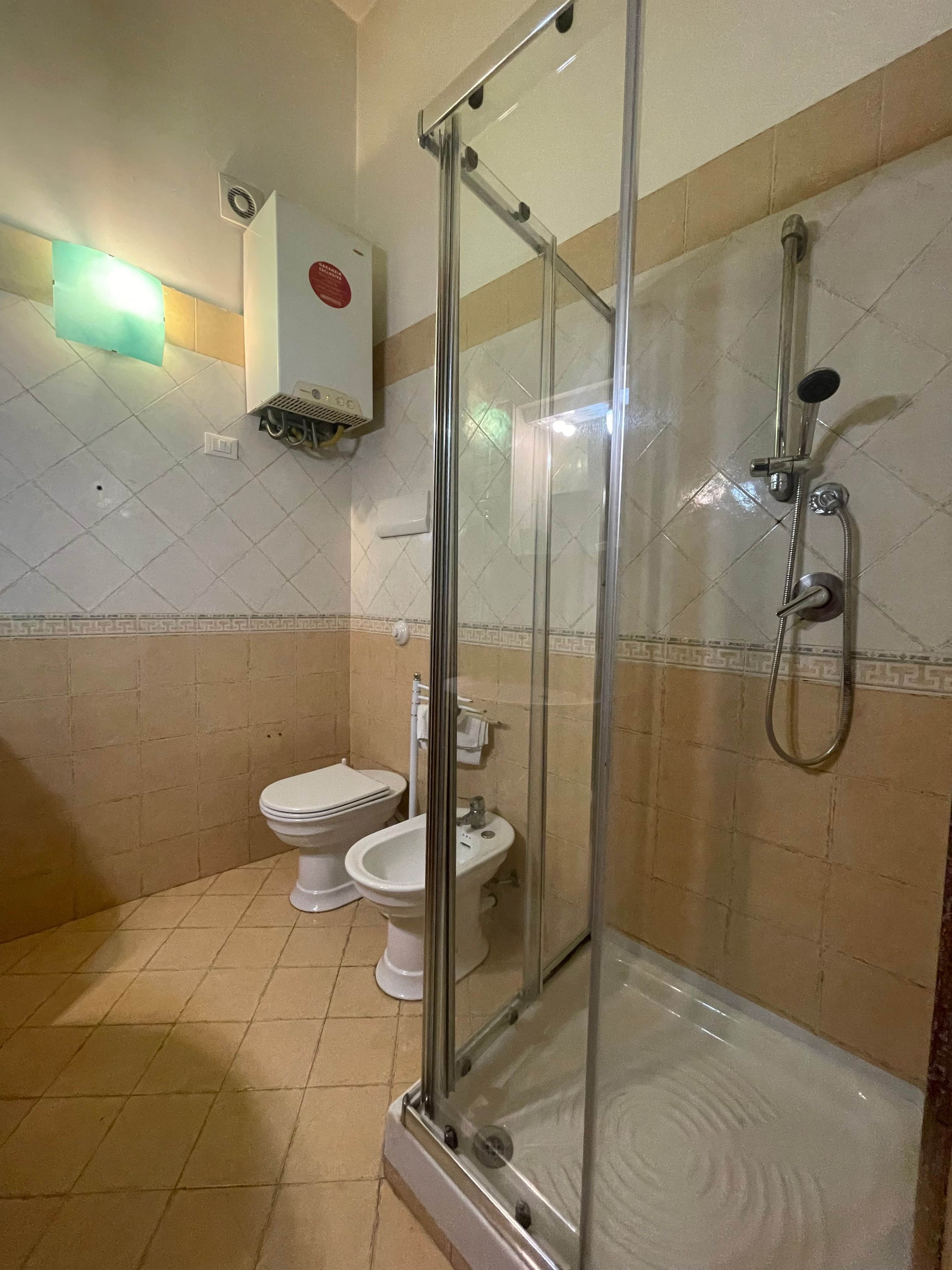 A bathroom with a glass-enclosed shower, a toilet, and a bidet.