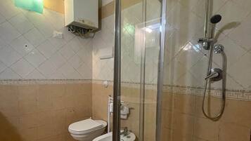 A bathroom with a glass-enclosed shower, a toilet, and a bidet.