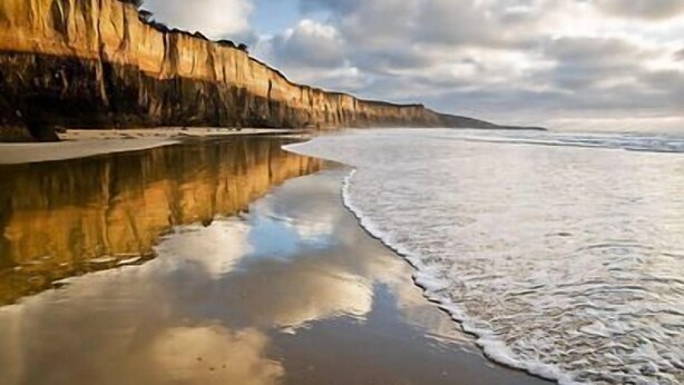 A beach with a sandy shore and a cliff. - Three Bedroom Bushland House (Anglesea)