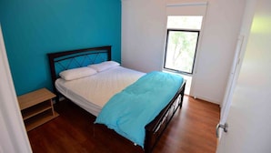 A bedroom with a bed, a window, and a door. - Three Bedroom Bushland House (Anglesea)