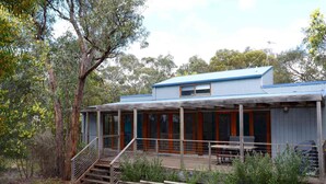 A rustic cabin with a covered porch, wooden steps, and a dining area. - Three Bedroom Bushland House (Anglesea)