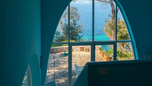 A room with a large arched window overlooking a rocky beach and the sea. - Beautiful villa overlooking the beach of Seccione (PORTOFERRAIO)