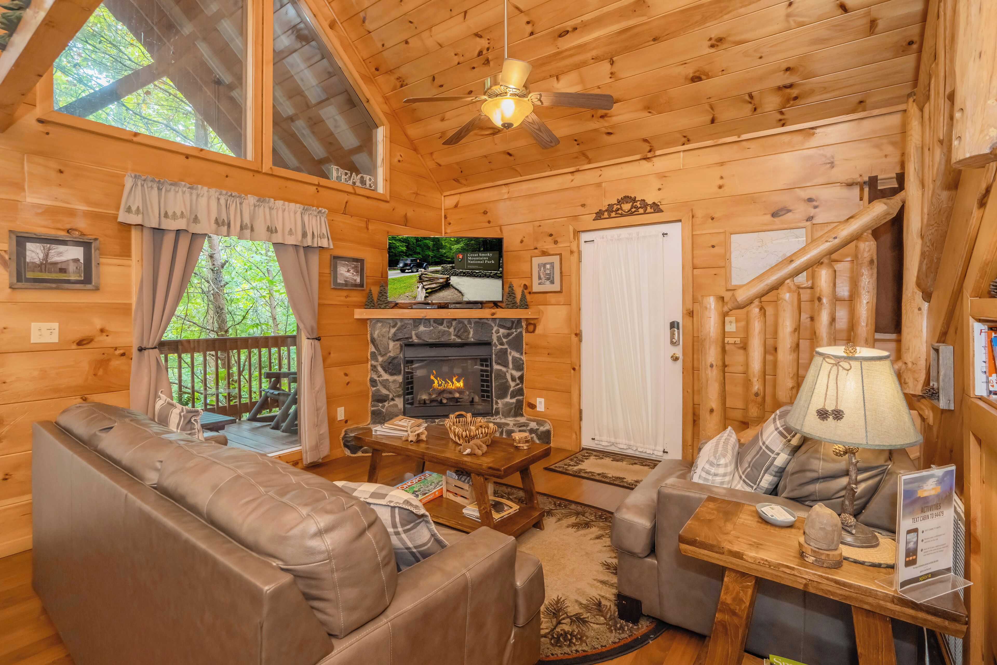 A cozy cabin interior with a stone fireplace, leather seating, and a wooden ceiling.