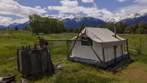 A tent set up in a grassy field with a mountain range in the background. - Glamping Tent at the base of the mountains outside Joseph, Oregon at Evans Farm. (Joseph)