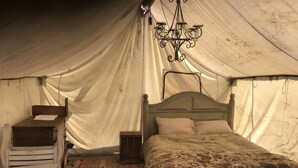 A tented room with a bed, a small table, and a chest of drawers. - Glamping Tent at the base of the mountains outside Joseph, Oregon at Evans Farm. (Joseph)
