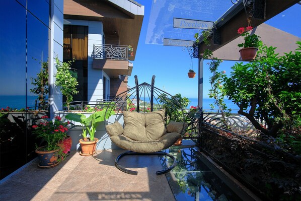 A balcony with a hanging chair, potted plants, and a clear view of the sea. - Peerless Villas Hotel (Trabzon)