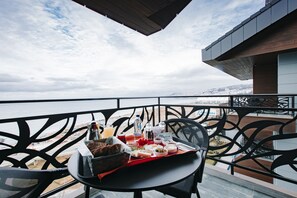 Un balcón con mesa lista para una comida, con vista a la playa y al océano.