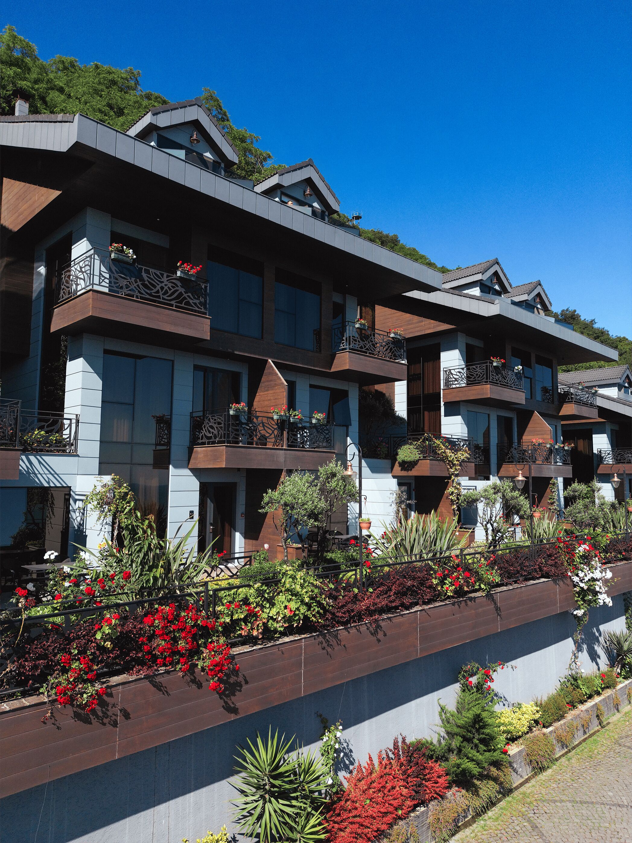 A multi-story hotel with balconies, large windows, and a landscaped garden area.