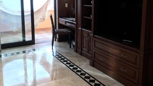 A spacious room with a large sliding glass door leading to a balcony, a wooden cabinet with drawers, and a tiled floor with a geometric pattern. - Fabulous Developers Beachfront PENTHOUSE XMAS & NY WKS @ Playa Grande Resort (Cabo San Lucas)