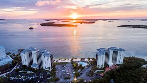 Ein hoch aufragendes Hotel mit mehreren Etagen, einem Parkplatz und Blick auf Wasser und Inseln bei Sonnenuntergang.