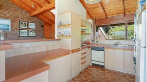 Una cocina con vigas de madera, pared de ladrillo y ventana con vistas.