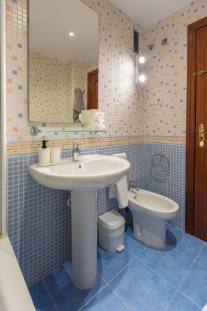 A bathroom with a large sink, a bidet, and a mirror.