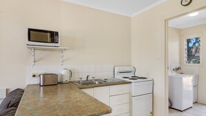 Eine kompakte Küche mit Mikrowelle, Toaster, Wasserkocher, Spüle, Herd und kleinem Kühlschrank.