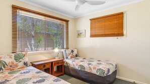 Ein Schlafzimmer mit zwei Einzelbetten, einem Nachttisch mit Lampe und einem Deckenventilator.