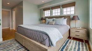 A bedroom with a large bed, two bedside tables, and a window with blinds. - Seaglass Shores: New 2BR/2BTH Modern Condo With Bay & Ocean Views (San Diego)