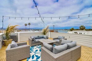 A rooftop patio with wicker furniture, string lights, and a view of the city.