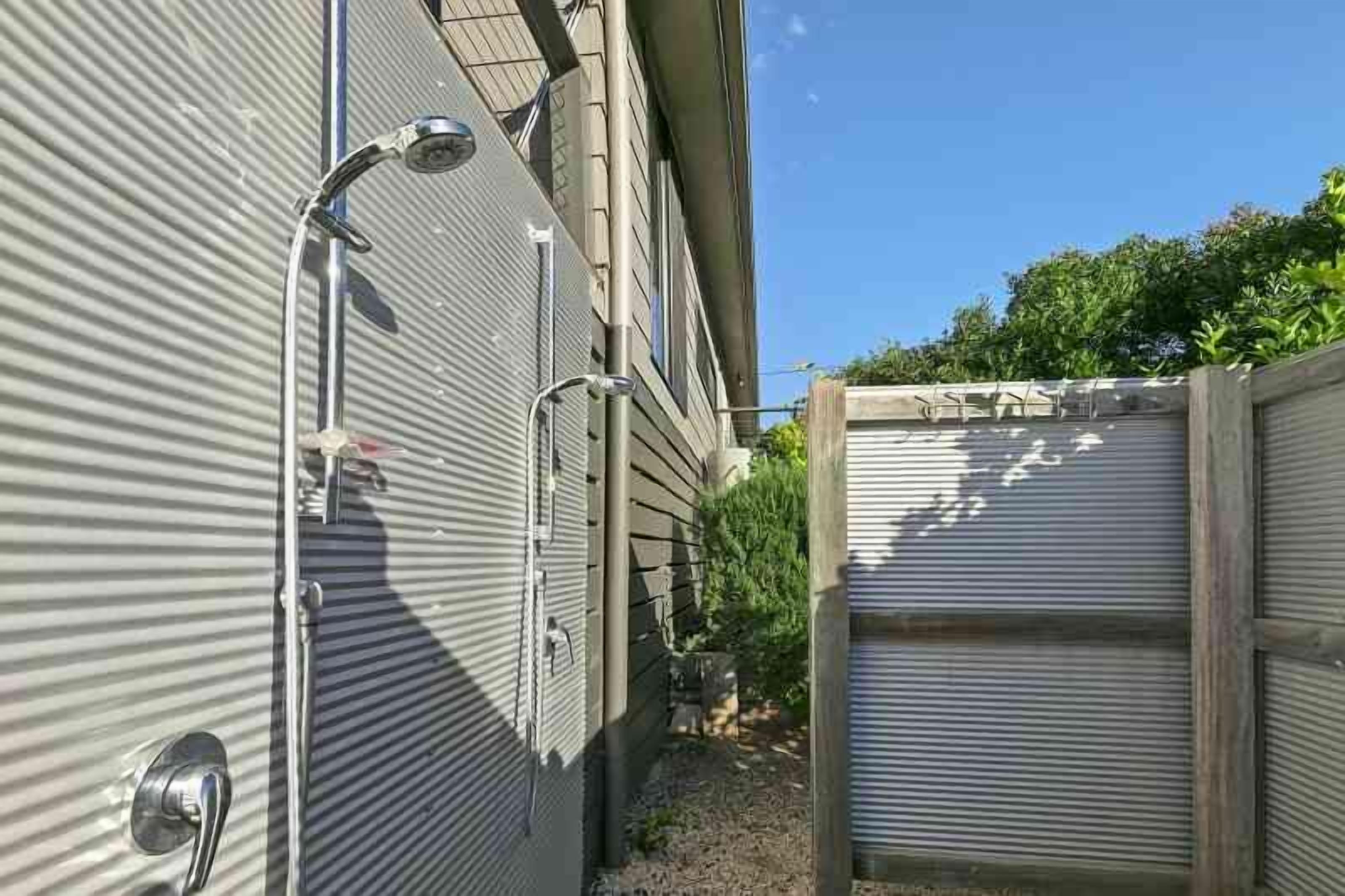 A narrow outdoor corridor with metal siding walls, a metal gate, and a small garden area with plants.