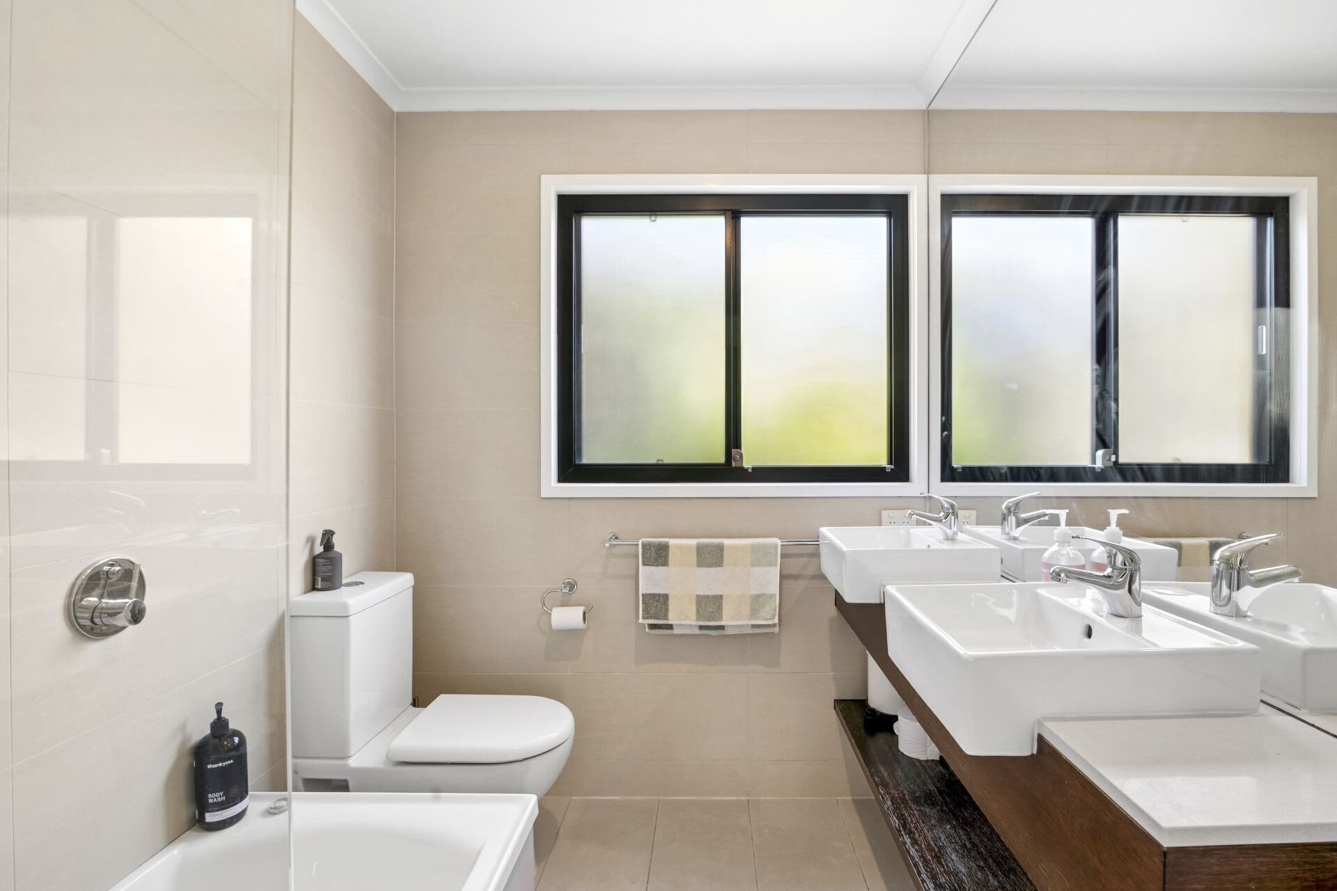 A modern bathroom with a toilet, bidet, and two sinks.