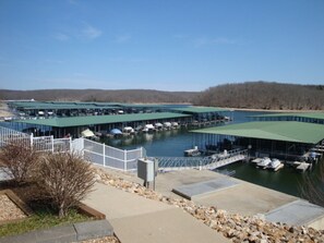 Moored boats line the marina's green-roofed docks, set amidst a serene natural landscape.