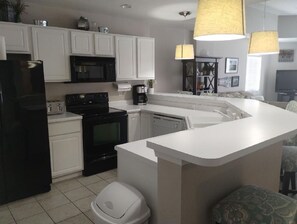 Kitchen features a refrigerator, stove, microwave, and sink.