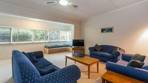 A living room with a sofa set, a coffee table, a television, and a ceiling fan. - Aireys Inlet Cottage (Aireys Inlet)