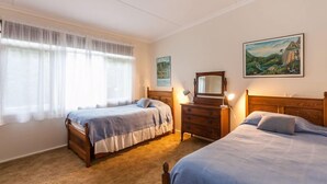 A bedroom with two beds, a dresser, a mirror, and a window with sheer curtains. - Aireys Inlet Cottage (Aireys Inlet)