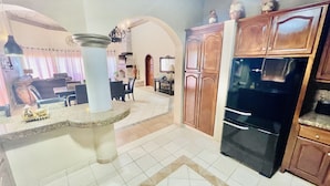 Una cocina con encimeras de granito, armarios de madera y un refrigerador negro.