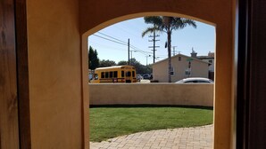 Un autobus scolaire jaune se trouve dans une rue, à proximité d’un panneau de signalisation indiquant un arrêt, avec un bâtiment en arrière-plan.