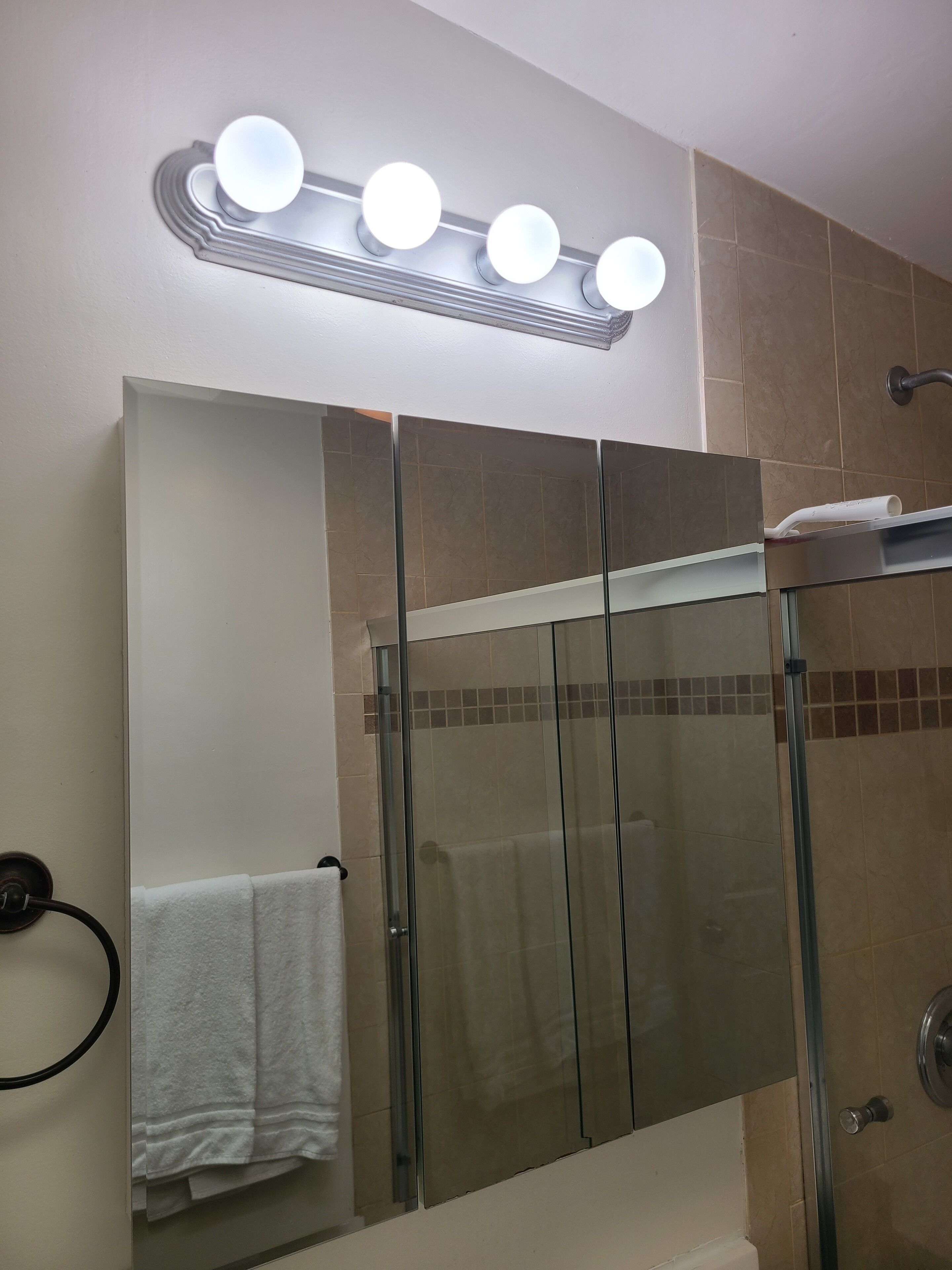 Un baño con cabina de ducha de vidrio, un espejo grande y un tocador con perchero.