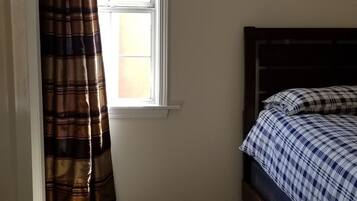A bedroom with a bed, a window, and a door.