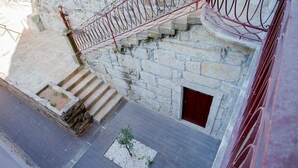 Ein Steinhaus mit einer roten Metalltreppe, die zu einer Tür führt.