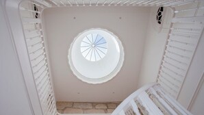 Ein Zimmer mit Dachfenster, weißen Geländern und Steinboden.
