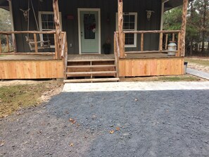 Eine rustikale Holzhütte mit Veranda, einer grünen Tür und einem kleinen Vorbereich mit einer Laterne.