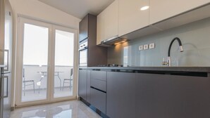 Een moderne keuken met een groot eiland, een inbouwoven en een strakke kraan.