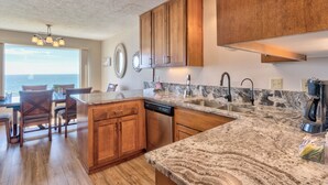 A kitchen with wooden cabinets, granite countertops, and a dishwasher.