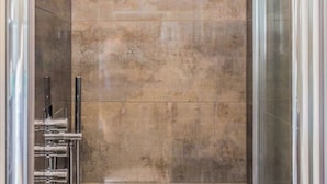 A bathroom with a large, textured wall and chrome fixtures. - 26 Penge House (London)