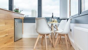 A modern kitchen with a wooden countertop, a built-in refrigerator, and a dining area with white chairs and a table. - 26 Penge House (London)