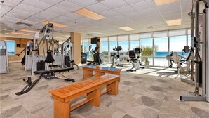 Une salle de sport équipée de machines de cardio, de postes d’entraînement avec poids et d’un banc.