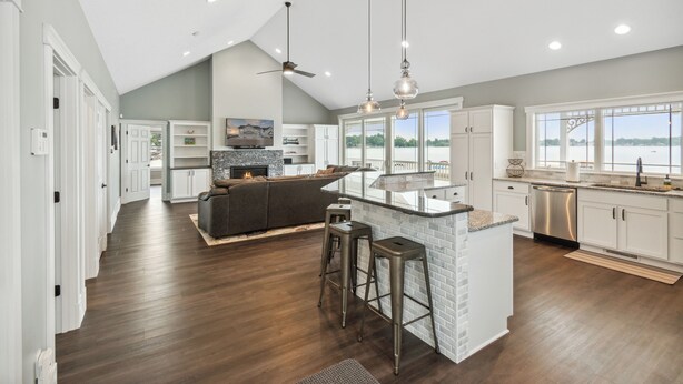 A spacious kitchen with a central island, white cabinetry, and a large window overlooking a scenic view. - Crystal Lakefront Luxury Condo – North Shore, Crystal, Michigan (Crystal)