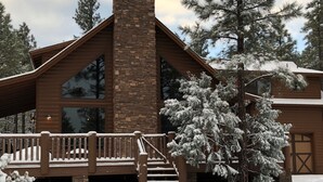 A lodge with a stone chimney, wooden deck, and snow-covered surroundings. - Torreon 3 BR home - Golf membership available (Show Low)
