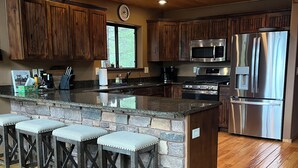 A modern kitchen with wooden cabinets, a stainless steel refrigerator, and a granite countertop. - Torreon 3 BR home - Golf membership available (Show Low)