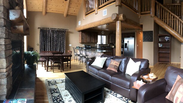 A spacious living area with a fireplace, leather sofa, dining table, and a wooden staircase. - Torreon 3 BR home - Golf membership available (Show Low)