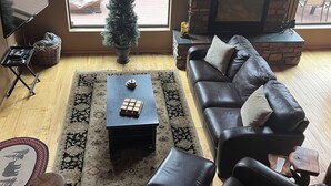 A living room with a fireplace, a large window, a television, and a Christmas tree. - Torreon 3 BR home - Golf membership available (Show Low)