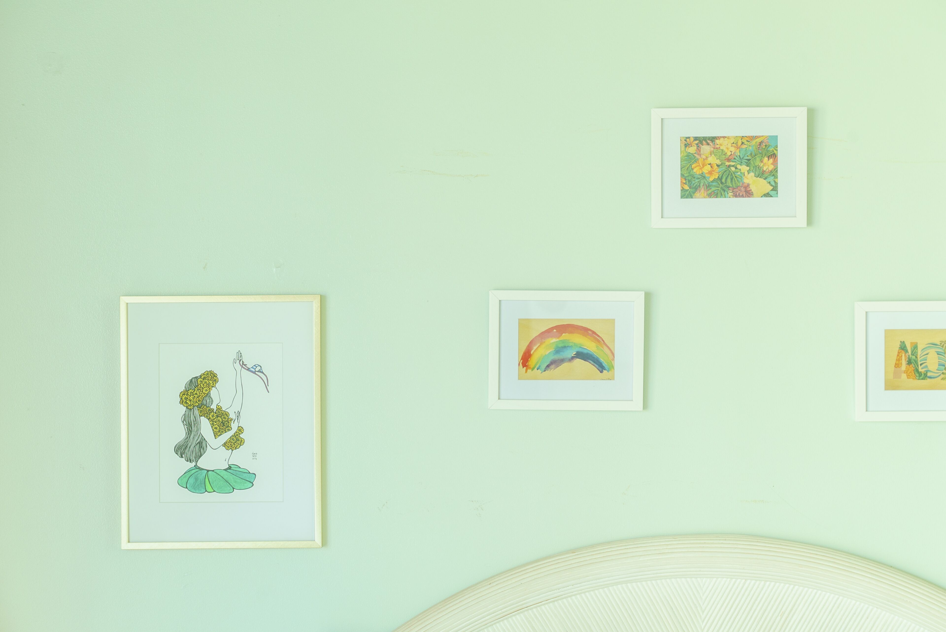 Een muur met vier ingelijste kunstwerken, waaronder een regenboog en een bloemistisch ontwerp.