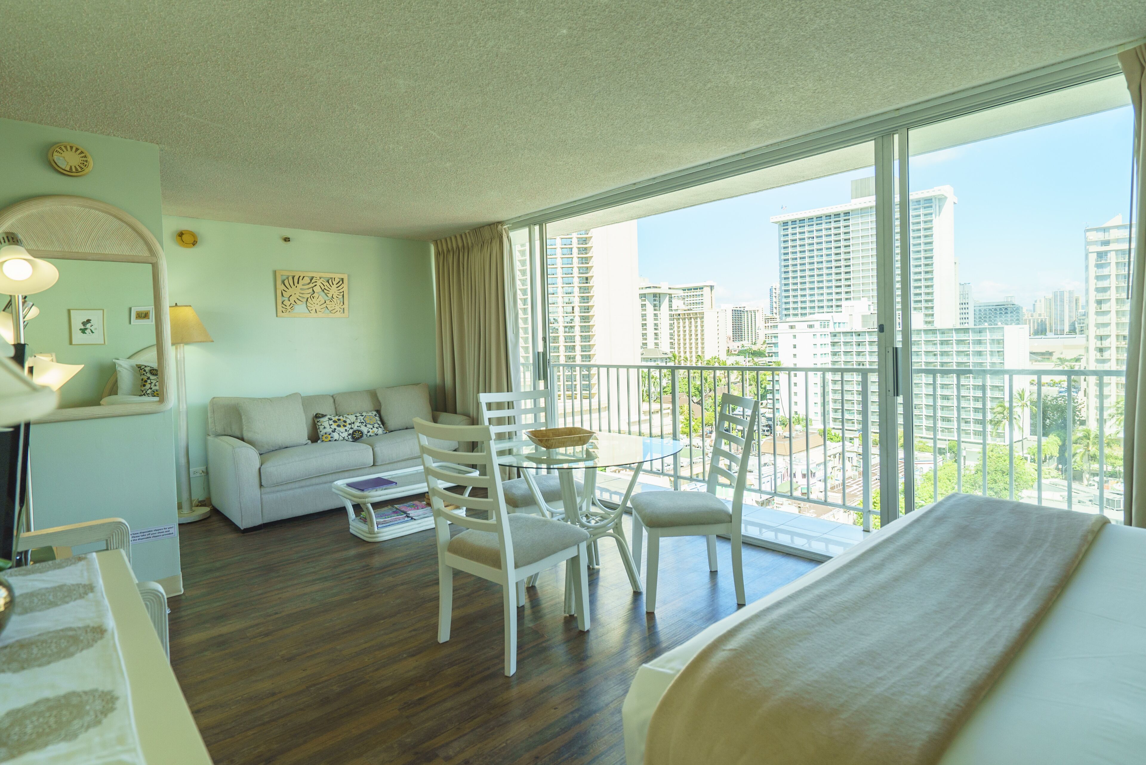 Una habitación de hotel con balcón, un sofá, una mesa de comedor y sillas.
