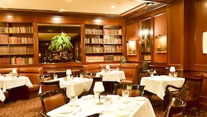A dining area with multiple tables set for guests, surrounded by bookshelves filled with books. - The Best Rate Ever!! Pacific Monarch Partial Ocean View Room!! (PM04) (Honolulu)