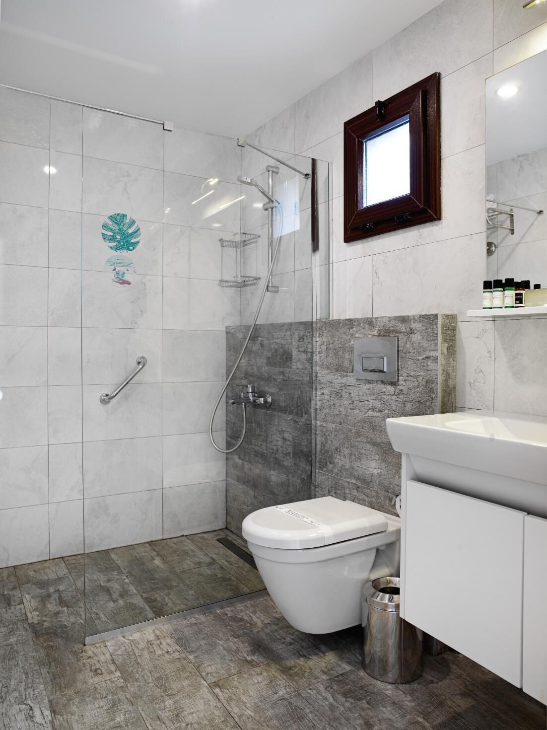 Un baño moderno con cabina de ducha de vidrio, inodoro blanco y tocador con espejo.