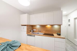 Una cocina compacta con armarios blancos, una encimera de madera y un lavavajillas integrado.