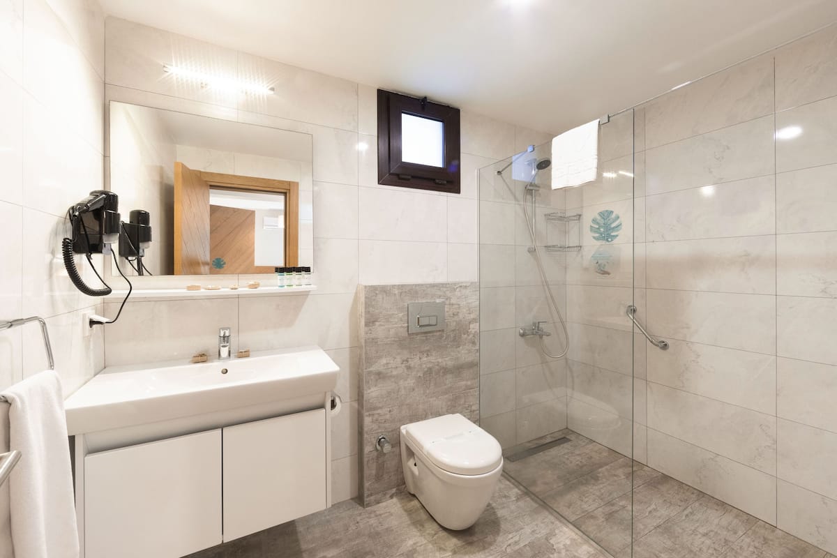 A modern bathroom with a sink, toilet, and glass shower enclosure.