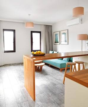 A modern kitchen with a wooden island, a teal sofa, and a dining table with stools.